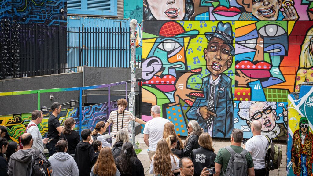 מדריך ומטיילים עומדים מול קיר גרפיטי, סיור גרפיטי בשורדיץ'
חודש ספטמבר בלונדון