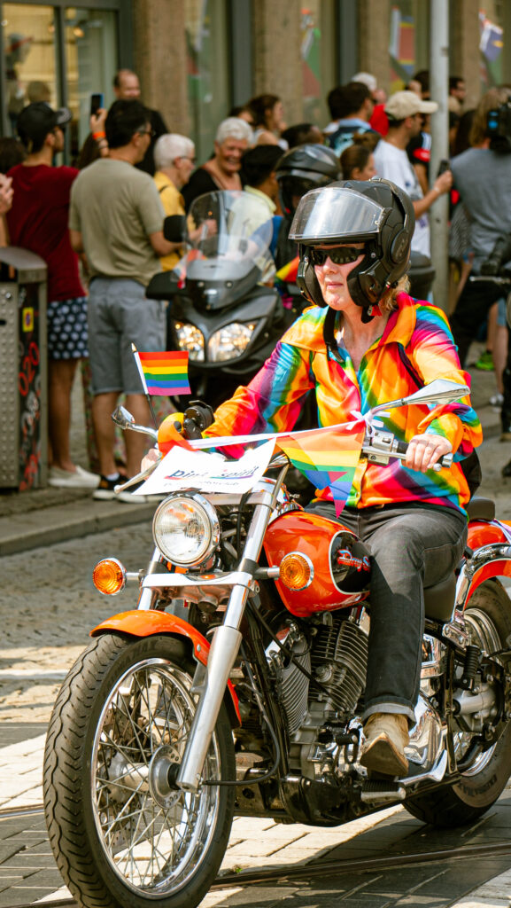 Person on a motorbike dressed up in rainbow-flagged clothes during the Pride Amsterdam