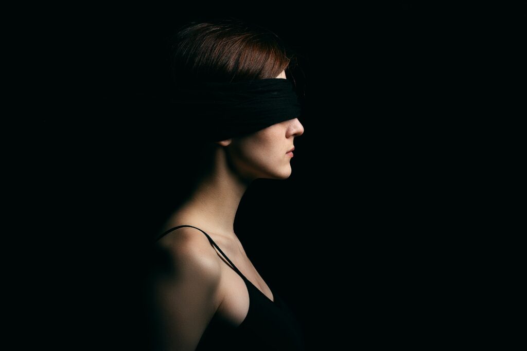 Woman with blindfold on in the dark.